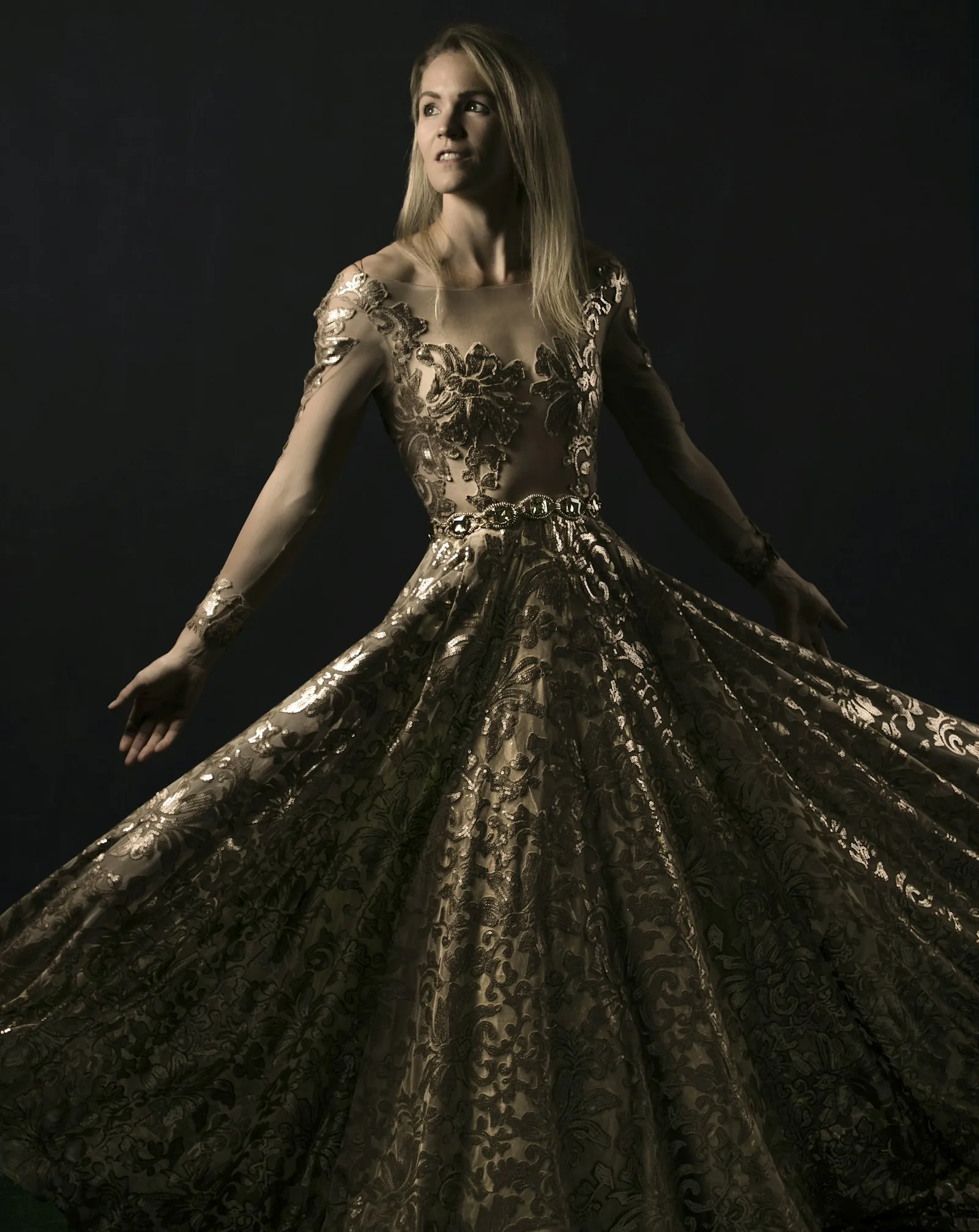 Robe longue brodée de fils dorés, présentée sur fond sombre